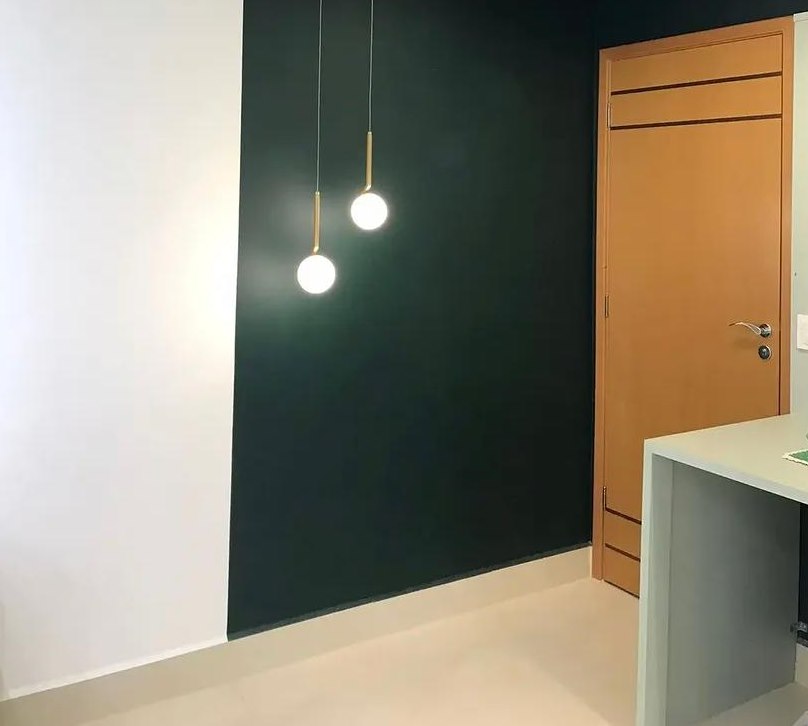 Ambiente comercial entregue com parede verde e pendentes dourados